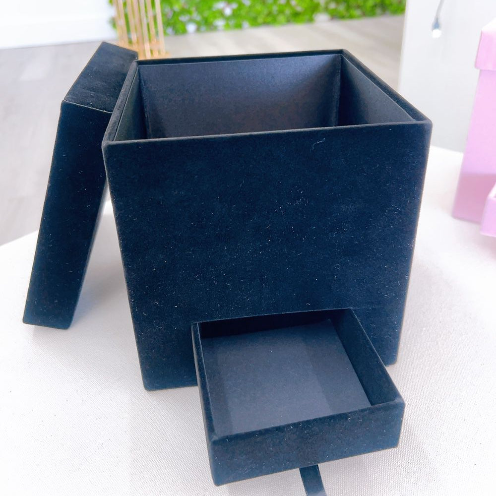 Blue jewelry box with a drawer on a white surface with a green blurred background