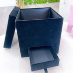 Blue jewelry box with a drawer on a white surface with a green blurred background