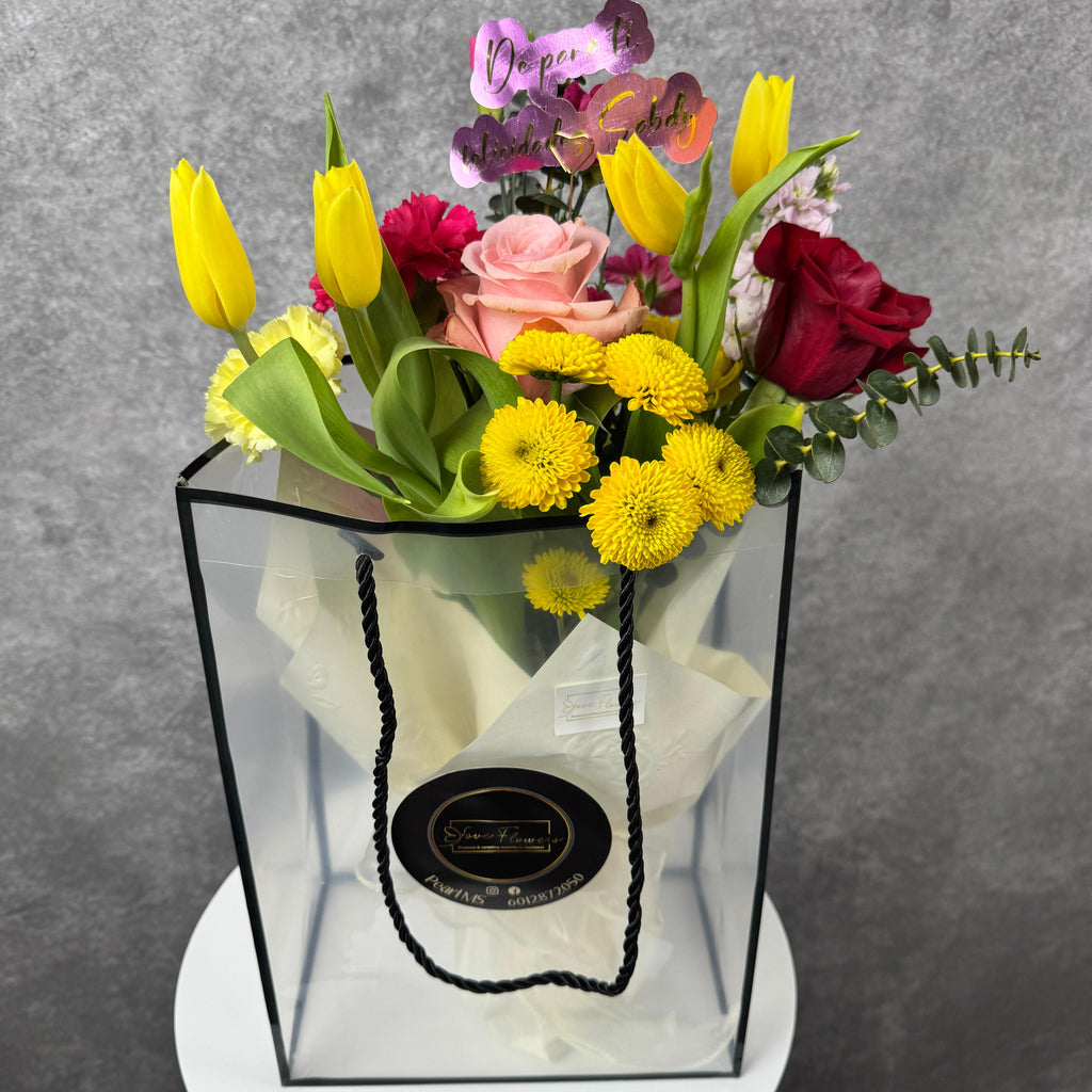 Colorful bouquet of flowers in a transparent box on a gray background