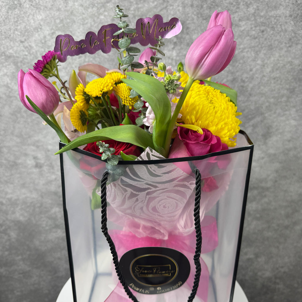 Colorful bouquet of flowers in a transparent gift bag with a gray background