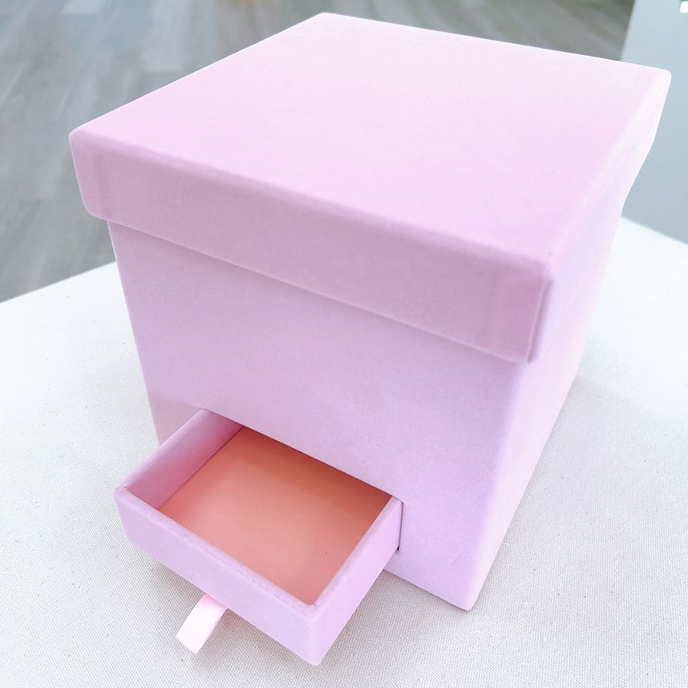 Pink jewelry box with a pink interior on a white surface.