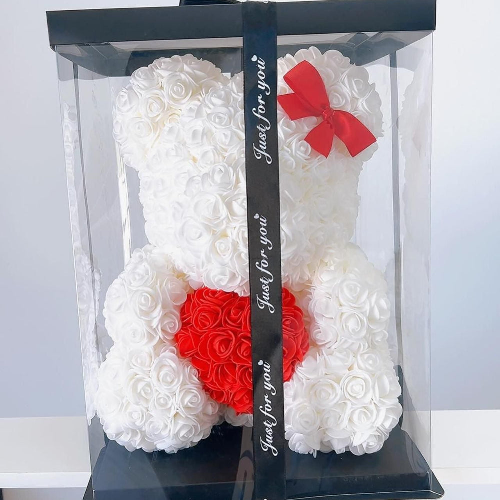 White rose teddy bear with red heart and bow in clear packaging on a white background