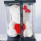 White rose teddy bear with red heart and bow in clear packaging on a white background